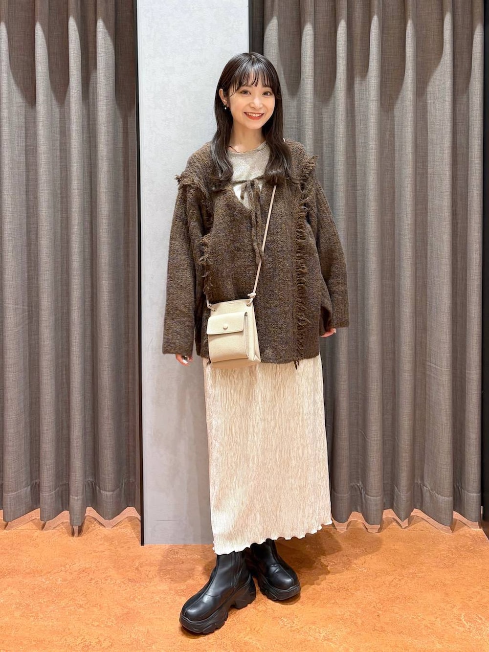 ブラウン系のニット/セーター、ホワイト系のTシャツ/カットソー、ブラック系のブーツを着用したレディースの冬コーディネートの2枚目の写真