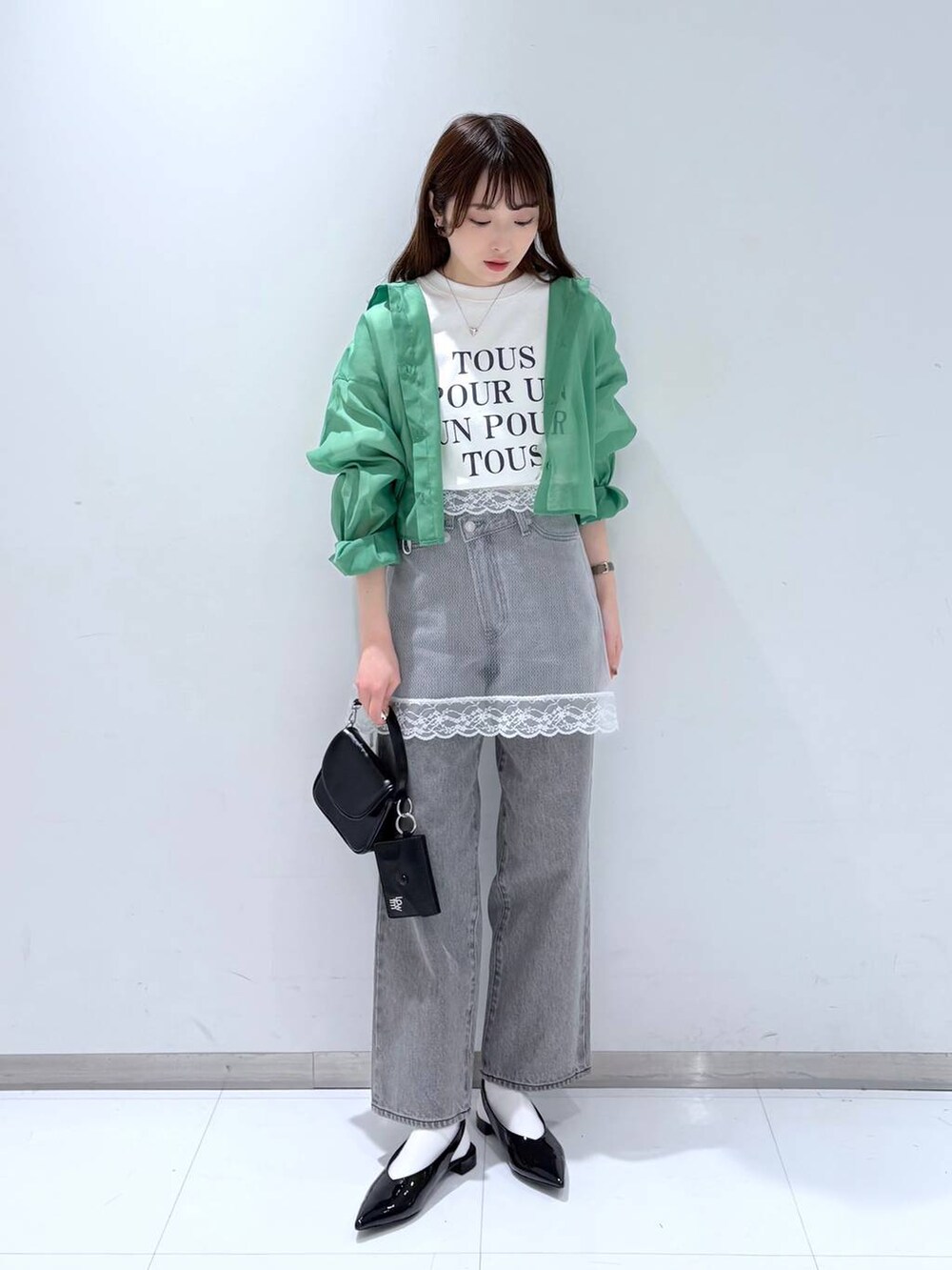 グリーン系のシャツ/ブラウス、グレー系のデニムパンツ、ブラック系のショルダーバッグを着用したレディースの春コーディネートの3枚目の写真