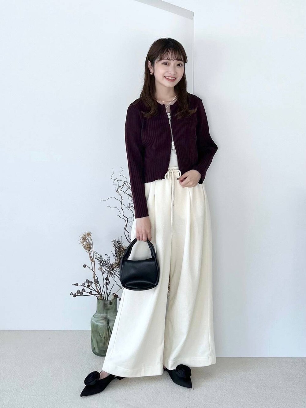 ブラック系のパンプス、ホワイト系のキャミソール、ブラック系のショルダーバッグを着用したレディースの夏コーディネートの2枚目の写真