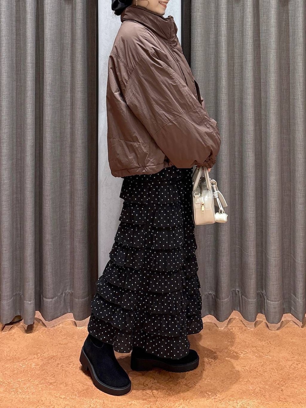 ブラウン系のその他アウター、その他のスカート、ホワイト系のボストンバッグを着用したレディースの冬コーディネートの3枚目の写真