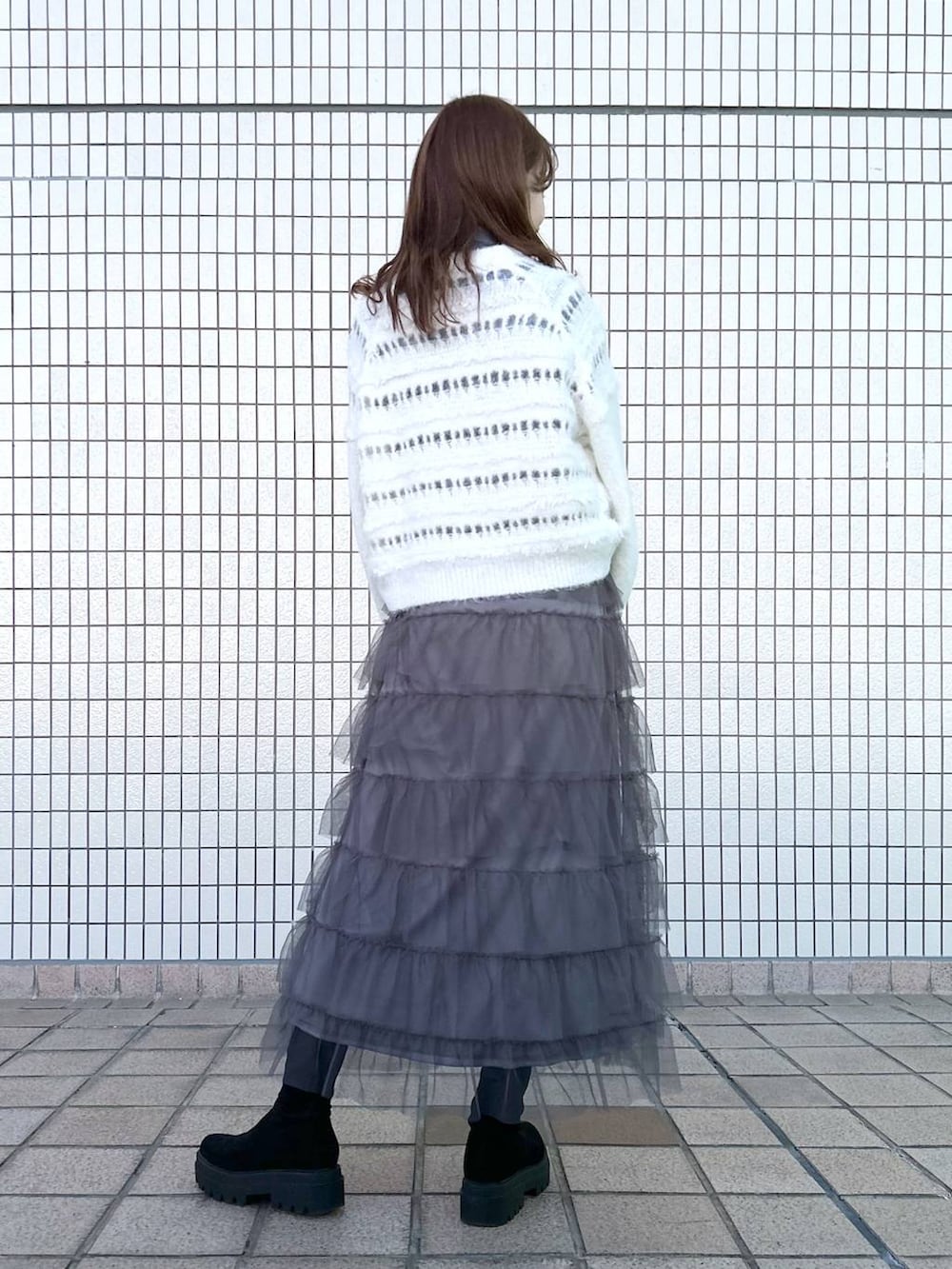 ブラック系のブーツ、グレー系のスカート、ホワイト系のニット/セーターを着用したレディースの冬コーディネートの3枚目の写真