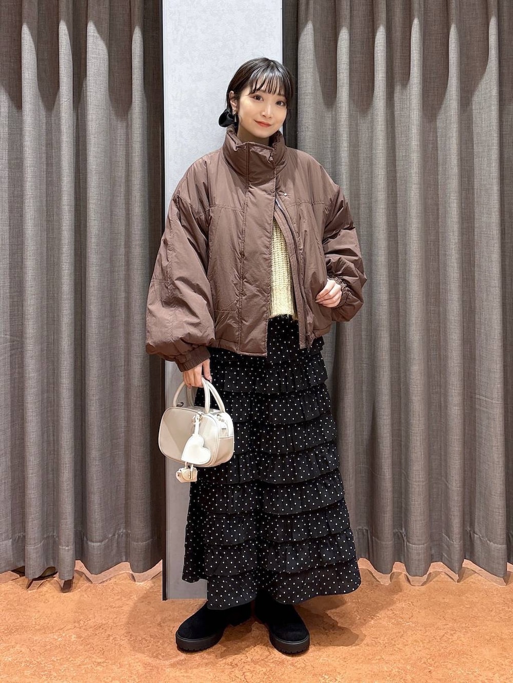 ブラウン系のその他アウター、その他のスカート、ホワイト系のボストンバッグを着用したレディースの冬コーディネートの2枚目の写真