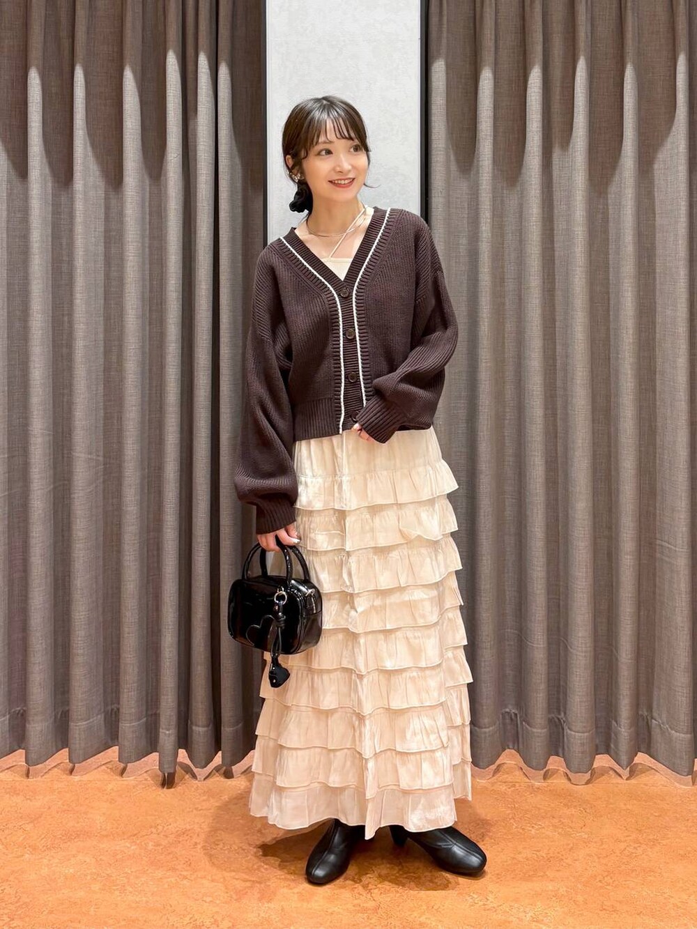 ベージュ系のキャミソール、ブラウン系のカーディガン/ボレロ、ブラック系のボストンバッグを着用したレディースの秋コーディネートの2枚目の写真