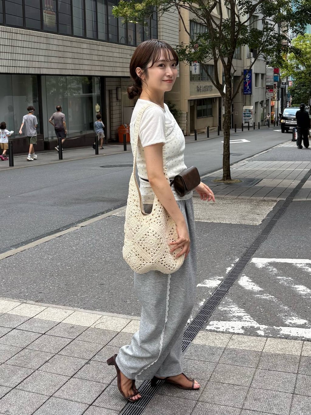 グレー系のスウェットパンツ、ブラウン系のボディバッグ/ウエストポーチ、ブラウン系のサンダルを着用したレディースの夏コーディネートの3枚目の写真