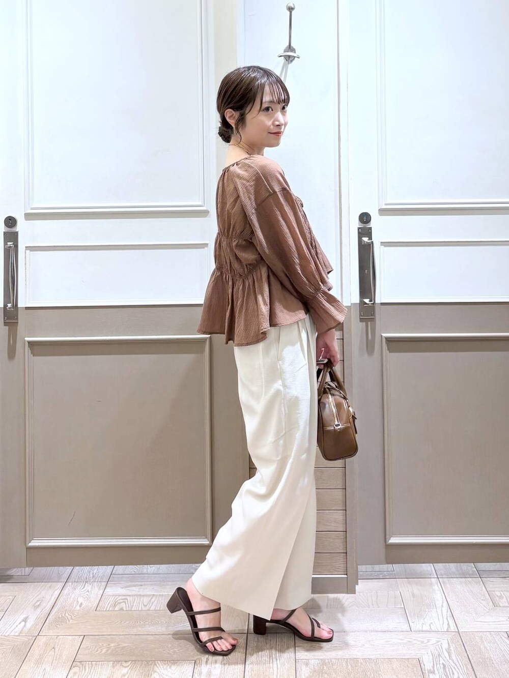 ホワイト系のスラックス、ブラウン系のシャツ/ブラウス、ゴールド系のタンクトップを着用したレディースの夏コーディネートの4枚目の写真