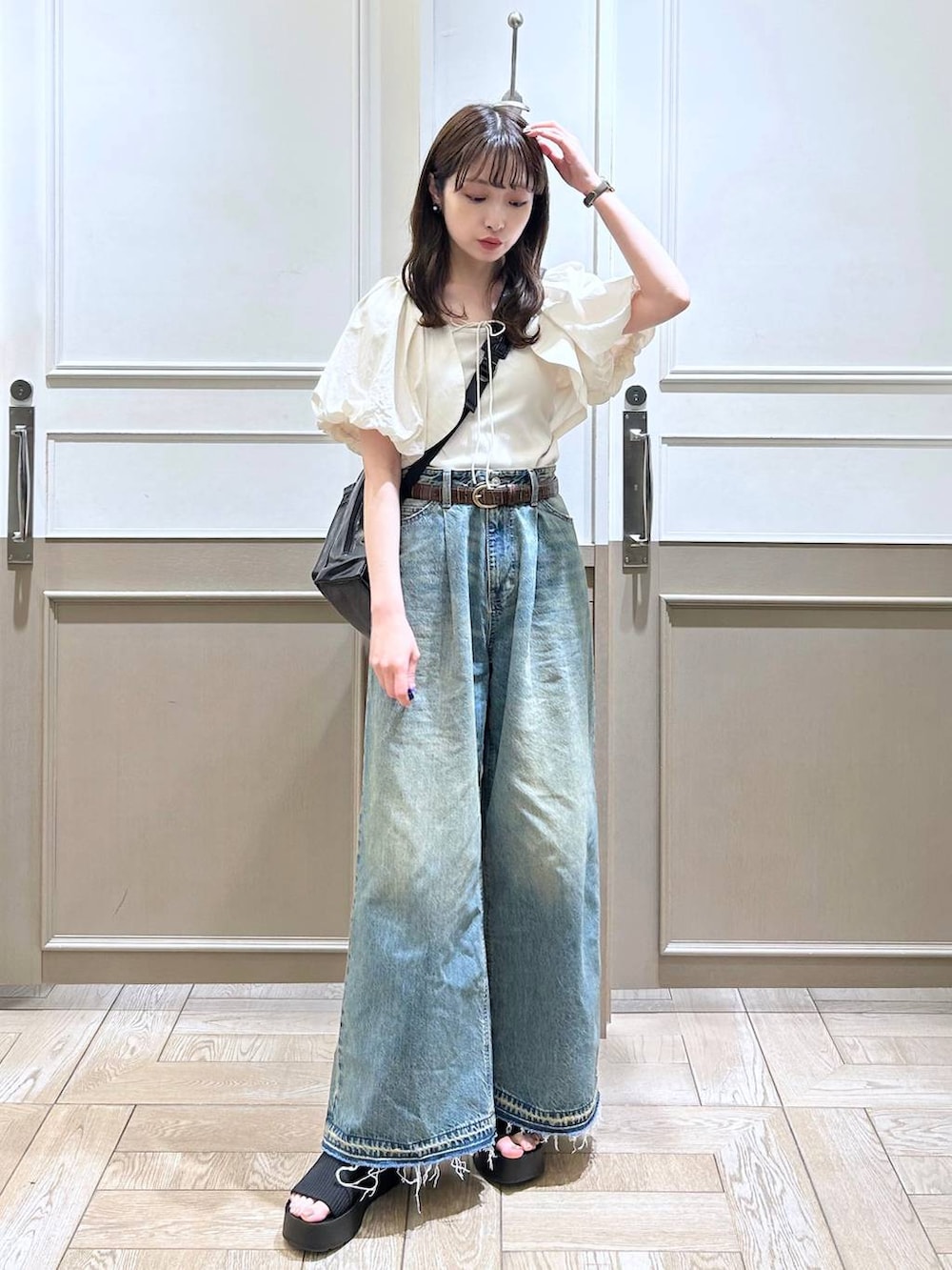 ホワイト系のTシャツ/カットソー、ブラック系のサンダル、ブルー系のデニムパンツを着用したレディースの春コーディネートの3枚目の写真