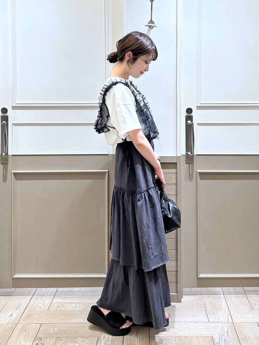 ブラック系のハンドバッグ、ブラック系のサンダル、ブラック系のベストを着用したレディースの夏コーディネートの5枚目の写真