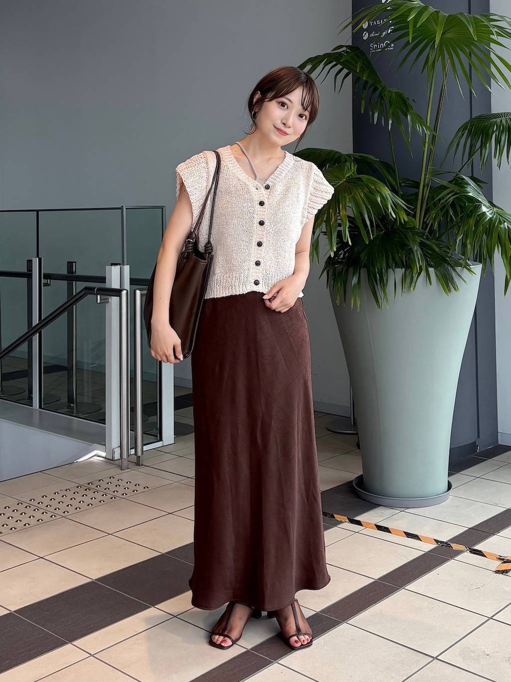 ブラウン系のスカート、ブラウン系のトートバッグ、ブラウン系のサンダルを着用したレディースの夏コーディネートの2枚目の写真