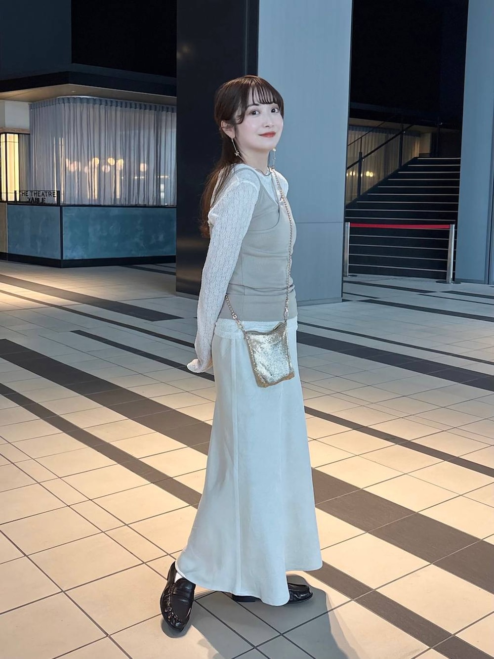 ゴールド系のショルダーバッグ、ホワイト系のスカート、ブラウン系のローファーを着用したレディースの春コーディネートの3枚目の写真