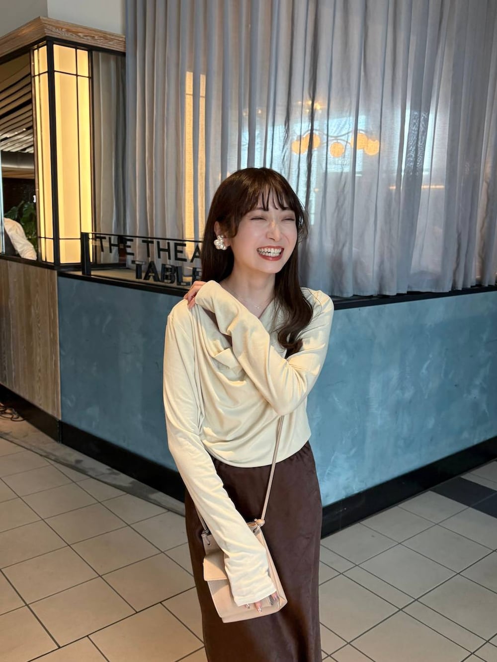 ブラウン系のスカート、ホワイト系のパンプス、ベージュ系のTシャツ/カットソーを着用したレディースの冬コーディネートの3枚目の写真