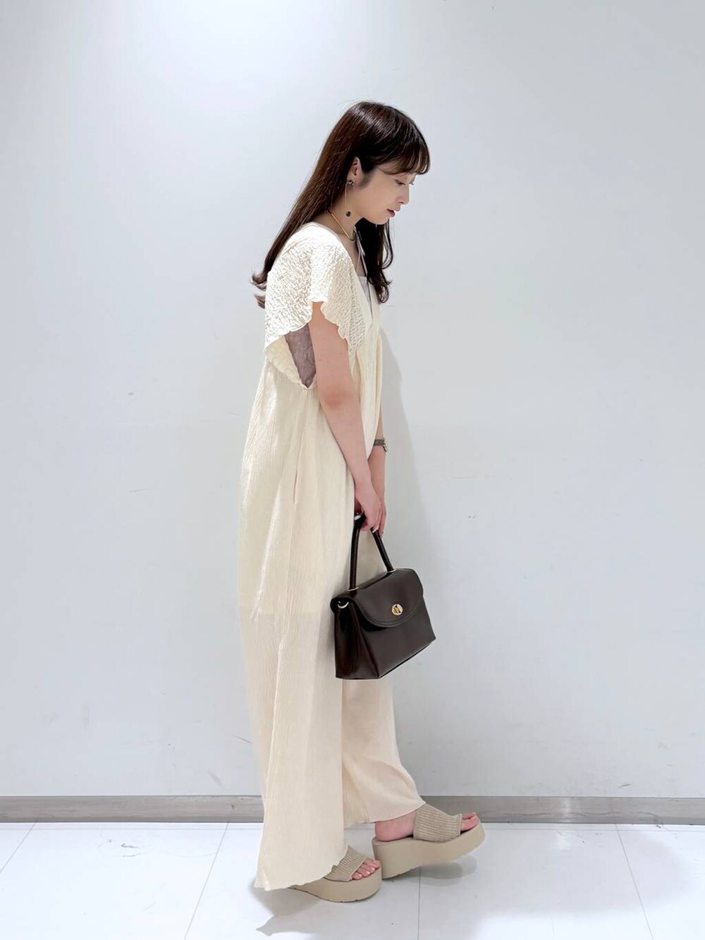 ホワイト系のサンダル、ホワイト系のサロペット/オーバーオール、ブラウン系のボストンバッグを着用したレディースの夏コーディネートの4枚目の写真