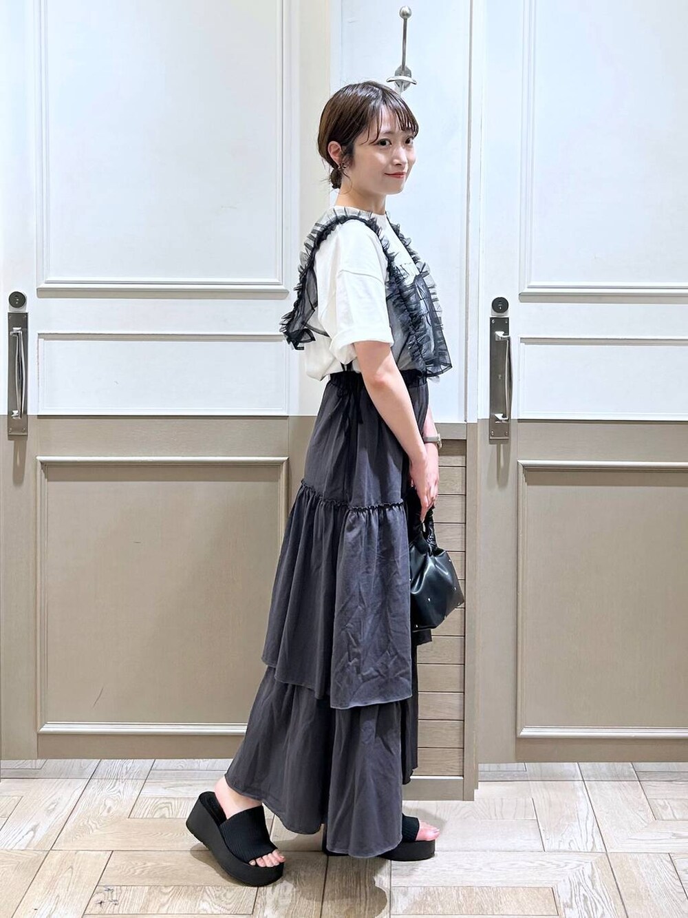 ブラック系のハンドバッグ、ブラック系のサンダル、ブラック系のベストを着用したレディースの夏コーディネートの4枚目の写真