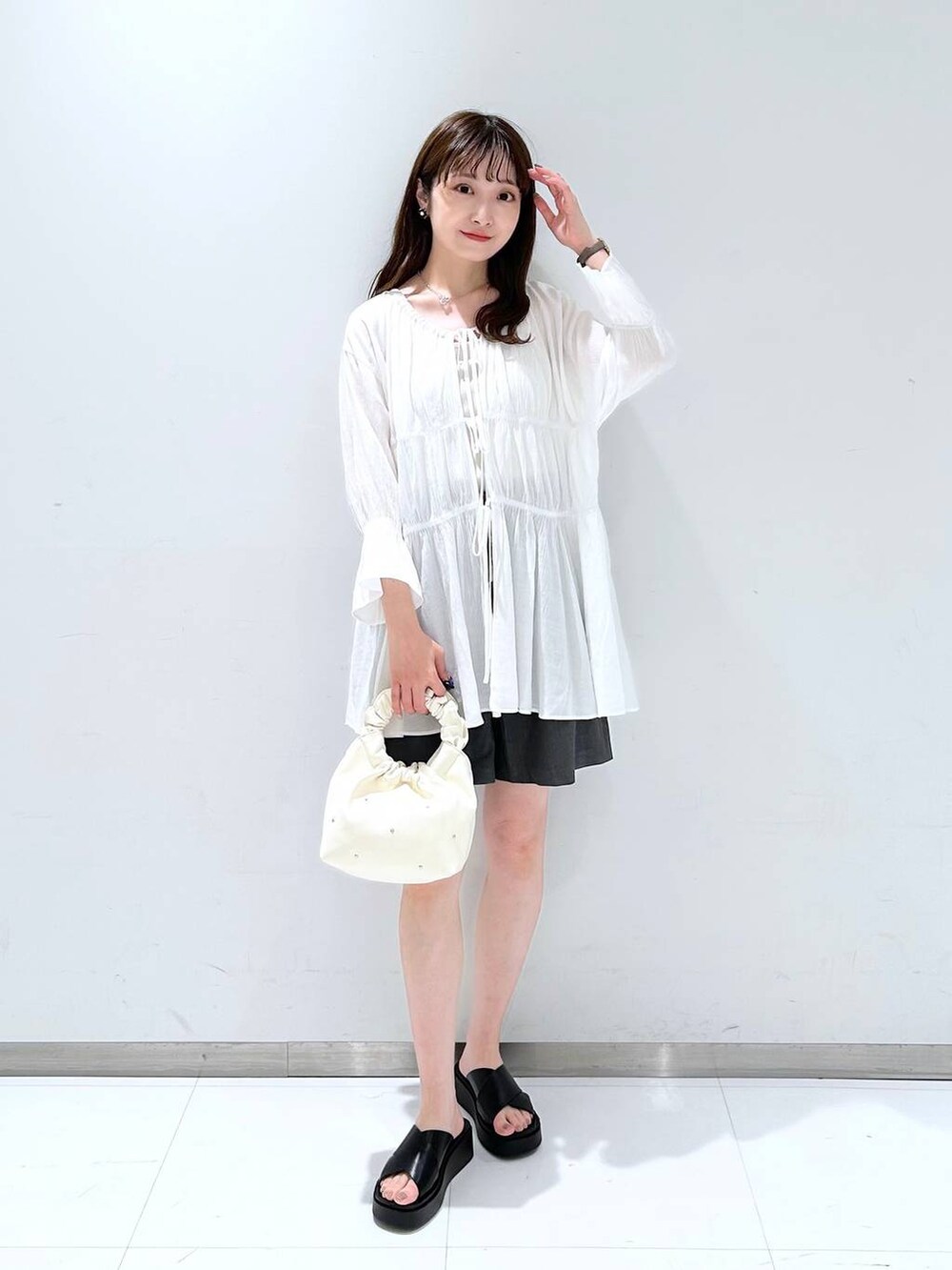 ベージュ系のハンドバッグ、ホワイト系のTシャツ/カットソー、ホワイト系のシャツ/ブラウスを着用したレディースの春コーディネートの3枚目の写真