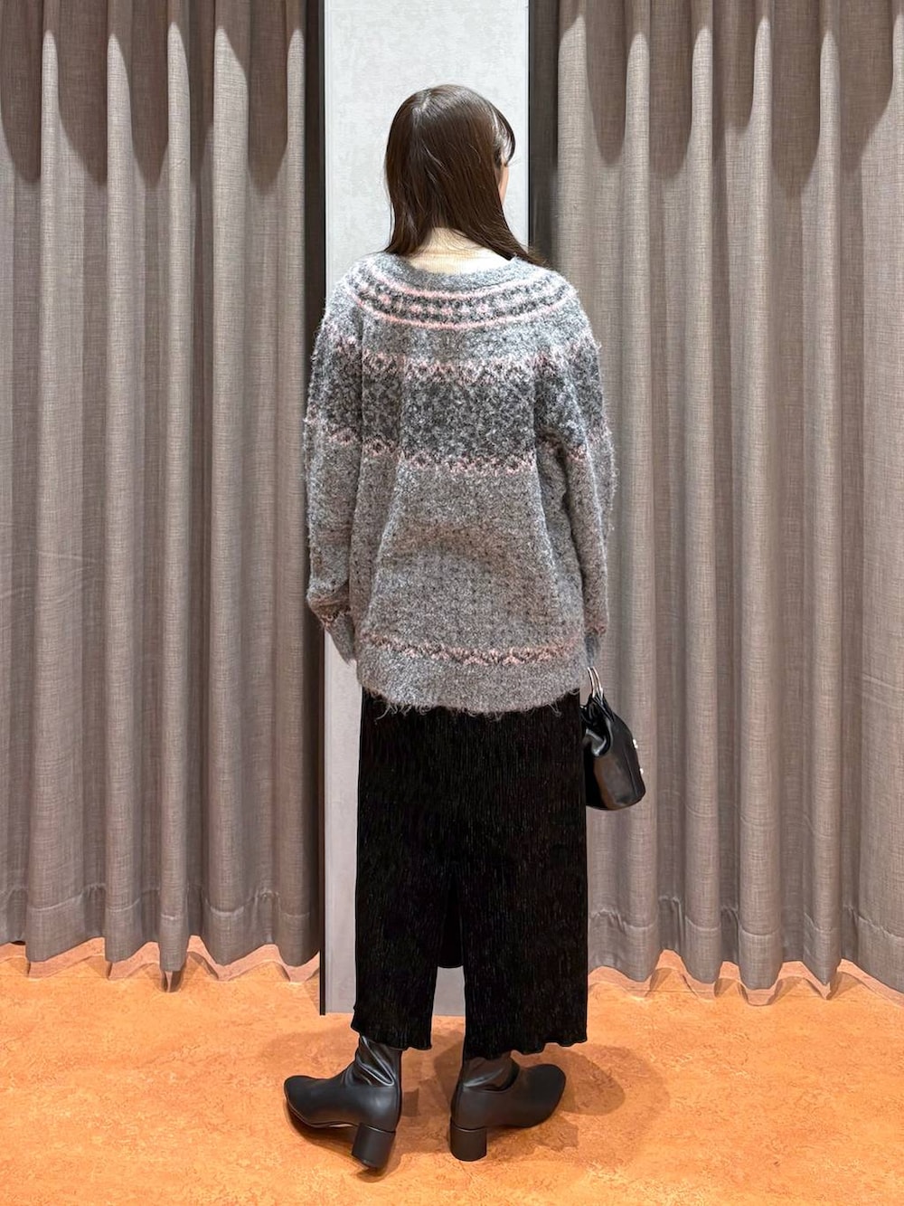 ホワイト系のニット/セーター、ブラック系のスカート、ブラック系のブーツを着用したレディースの冬コーディネートの4枚目の写真