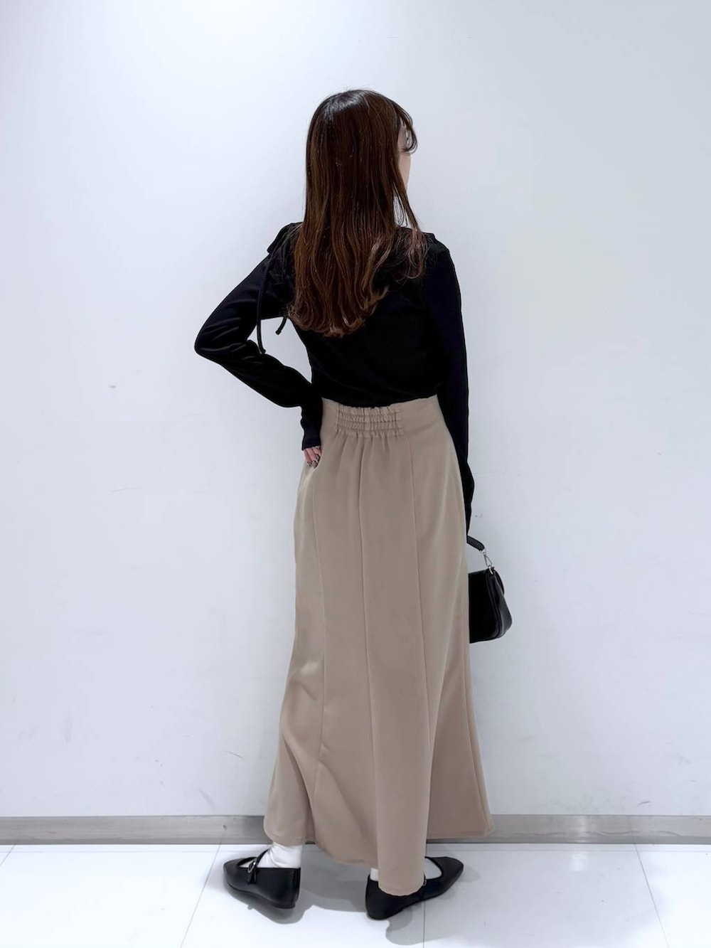 ブラック系のバレエシューズ、ブラック系のショルダーバッグ、ベージュ系のスカートを着用したレディースの冬コーディネートの5枚目の写真