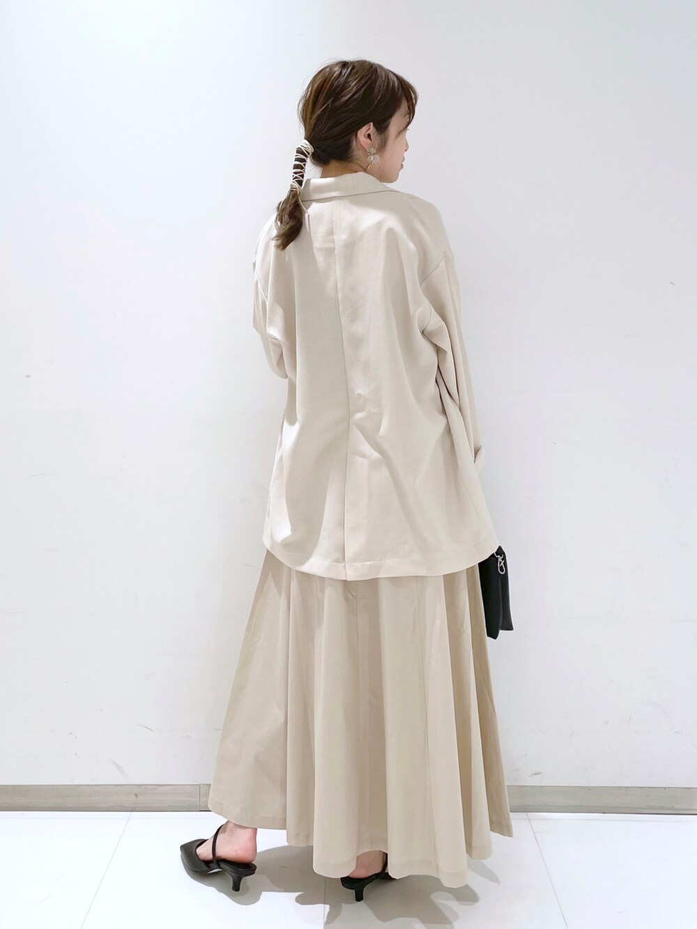 ブラック系のパンプス、ブラック系のショルダーバッグ、ホワイト系のスカートを着用したレディースの春コーディネートの2枚目の写真