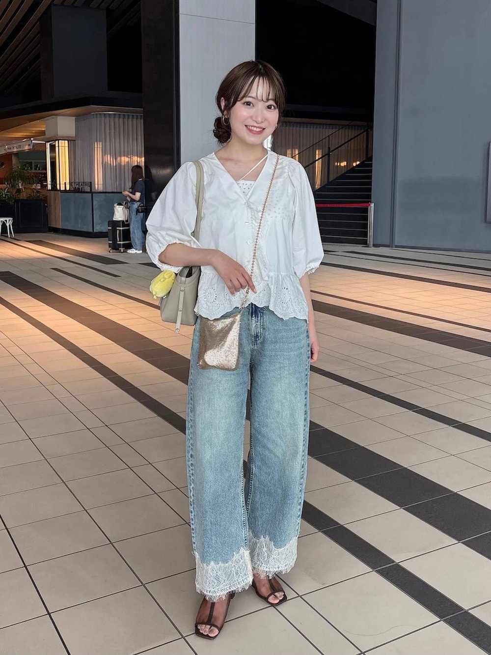 ゴールド系のショルダーバッグ、ブルー系のデニムパンツ、ホワイト系のシャツ/ブラウスを着用したレディースの夏コーディネートの2枚目の写真