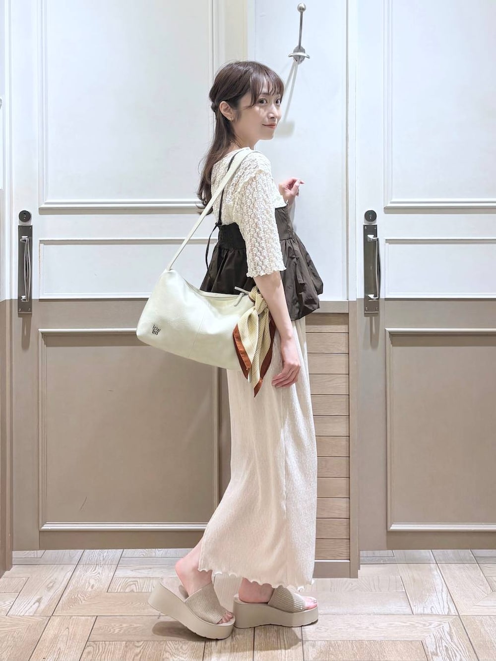 ホワイト系のTシャツ/カットソー、ホワイト系のサンダル、ブラック系のショルダーバッグを着用したレディースの春コーディネートの3枚目の写真