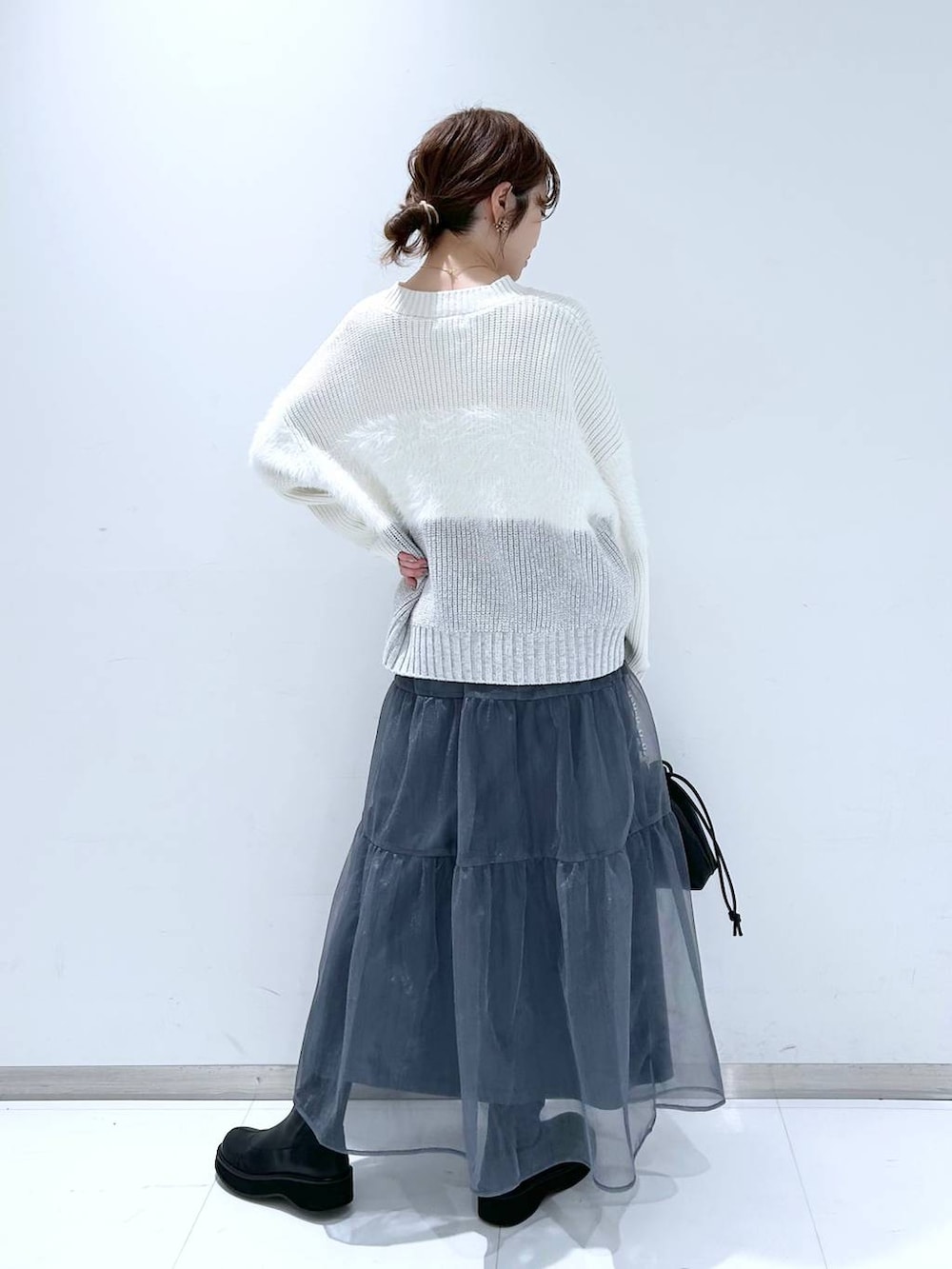 ブラック系のブーツ、ホワイト系のニット/セーター、グレー系のスカートを着用したレディースの冬コーディネートの5枚目の写真