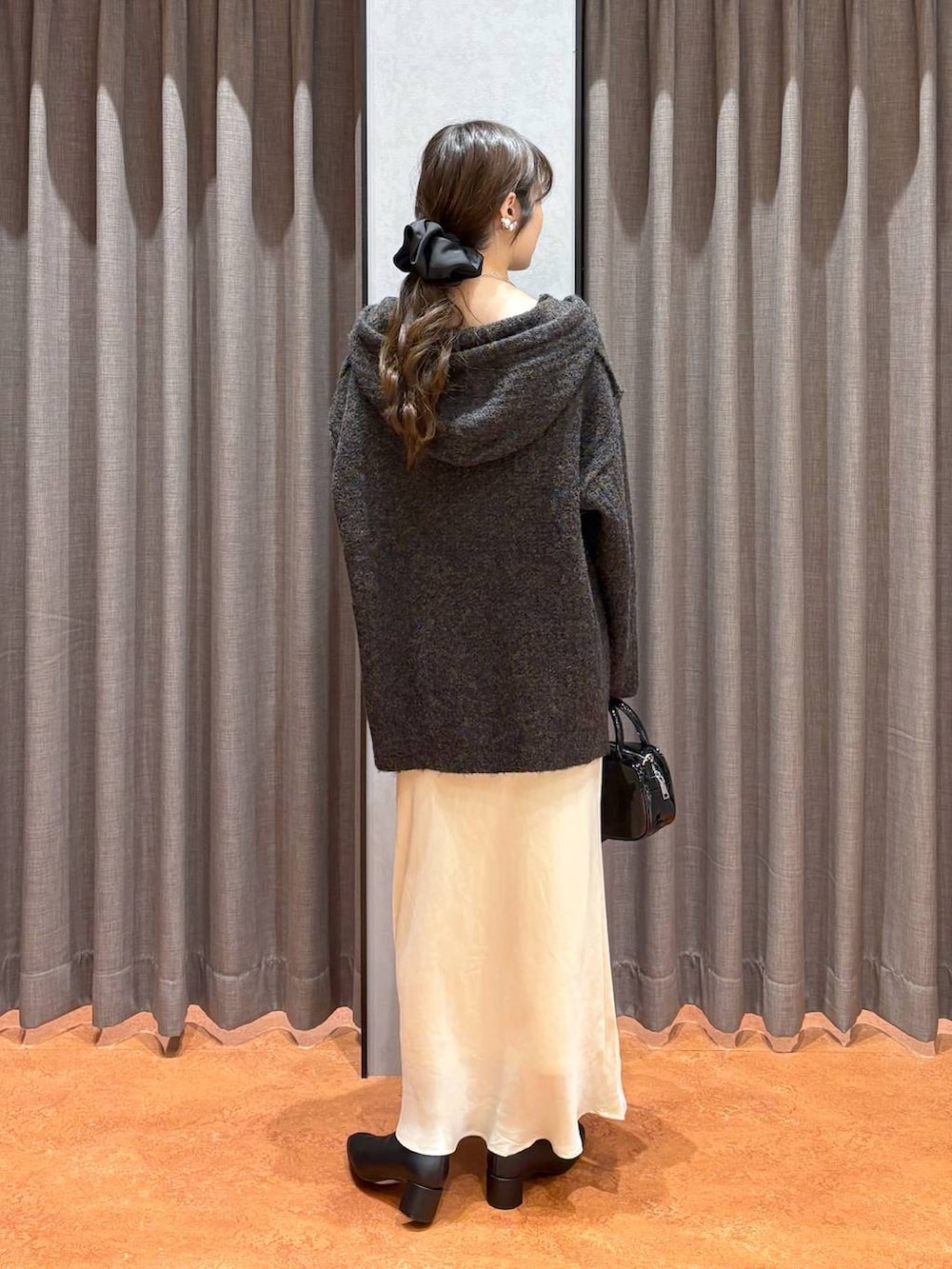 ベージュ系のキャミソール、ホワイト系のスカート、ブラック系のボストンバッグを着用したレディースの秋コーディネートの5枚目の写真