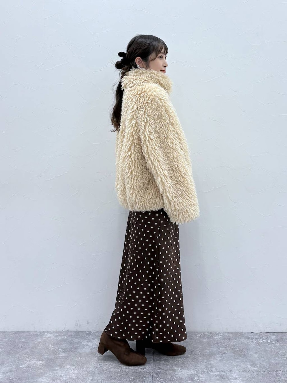 ブラウン系のスカート、ブラウン系のブーツ、ホワイト系のブルゾンを着用したレディースの秋コーディネートの3枚目の写真