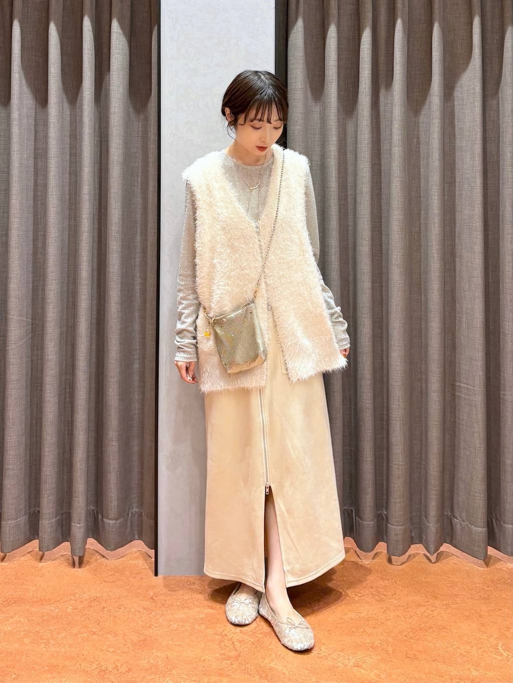 ゴールド系のショルダーバッグ、ホワイト系のスカート、ホワイト系のTシャツ/カットソーを着用したレディースの秋コーディネートの2枚目の写真