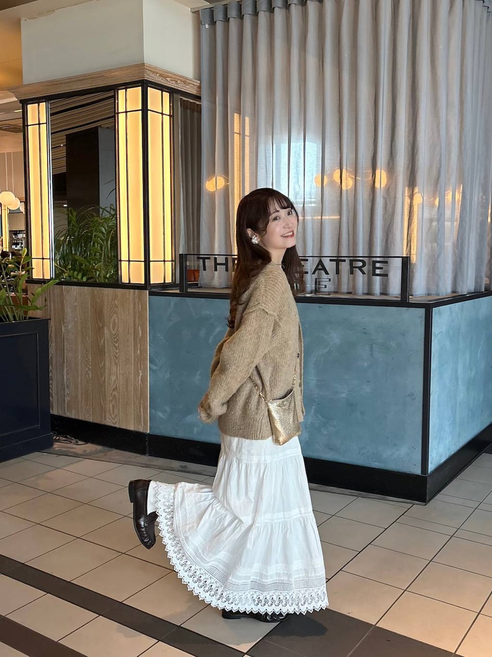 ゴールド系のショルダーバッグ、ブラウン系のローファー、ホワイト系のスカートを着用したレディースの春コーディネートの3枚目の写真