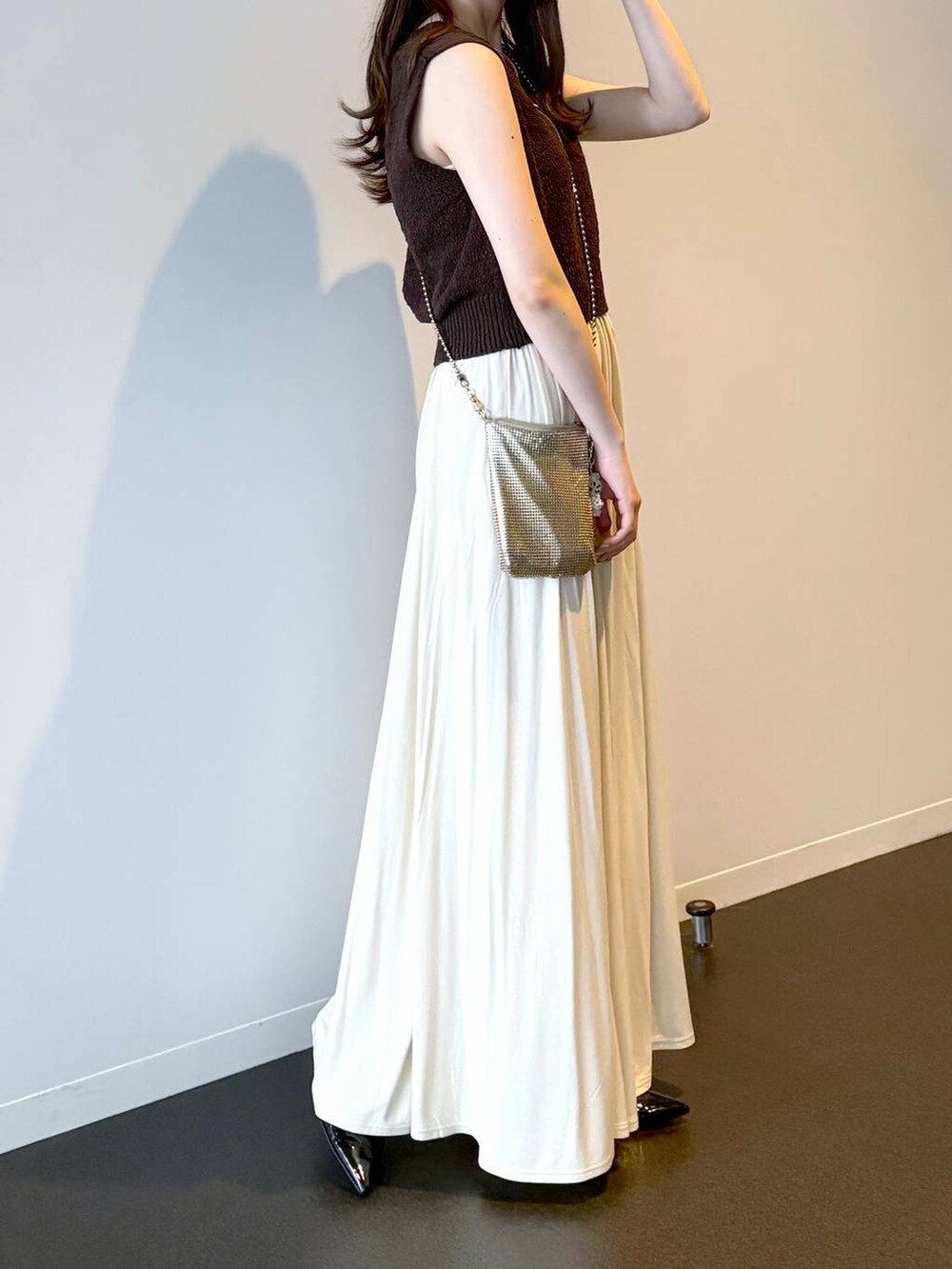 ゴールド系のショルダーバッグ、ブラック系のパンプス、ブラウン系のニット/セーターを着用したレディースの夏コーディネートの3枚目の写真