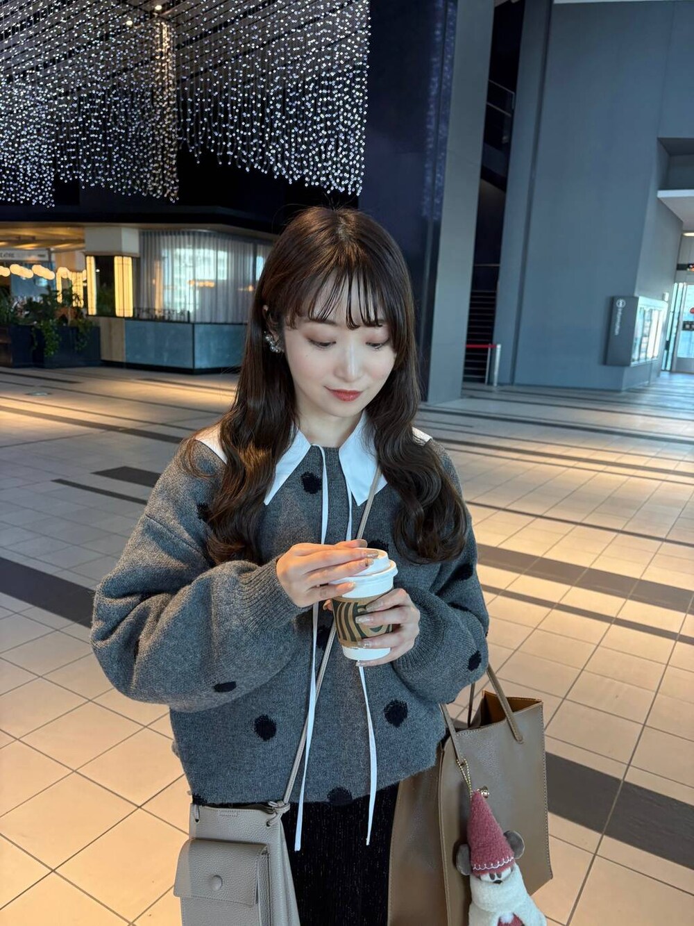 ブラック系のスカート、ホワイト系のシャツ/ブラウス、グレー系のニット/セーターを着用したレディースの冬コーディネートの3枚目の写真