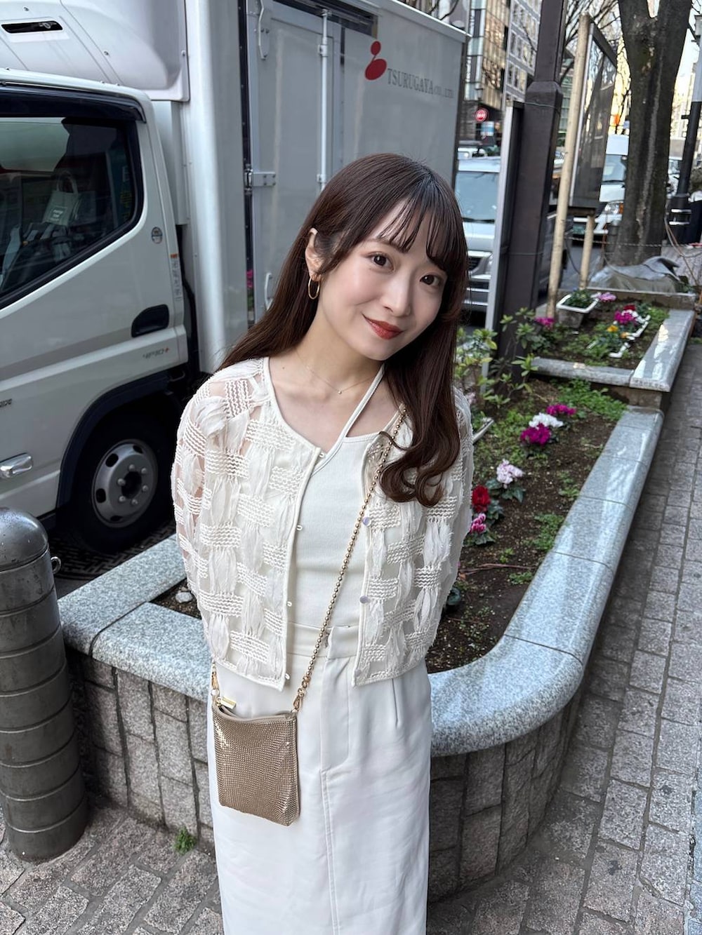 ゴールド系のショルダーバッグ、ホワイト系のパンプスを着用したレディースの春コーディネートの5枚目の写真