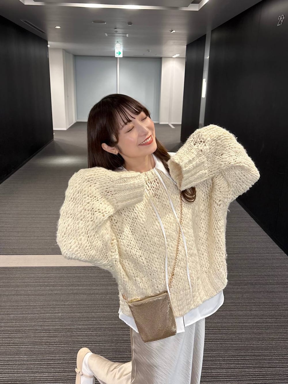 ゴールド系のショルダーバッグ、ホワイト系のニット/セーター、ホワイト系のシャツ/ブラウスを着用したレディースの秋コーディネートの4枚目の写真