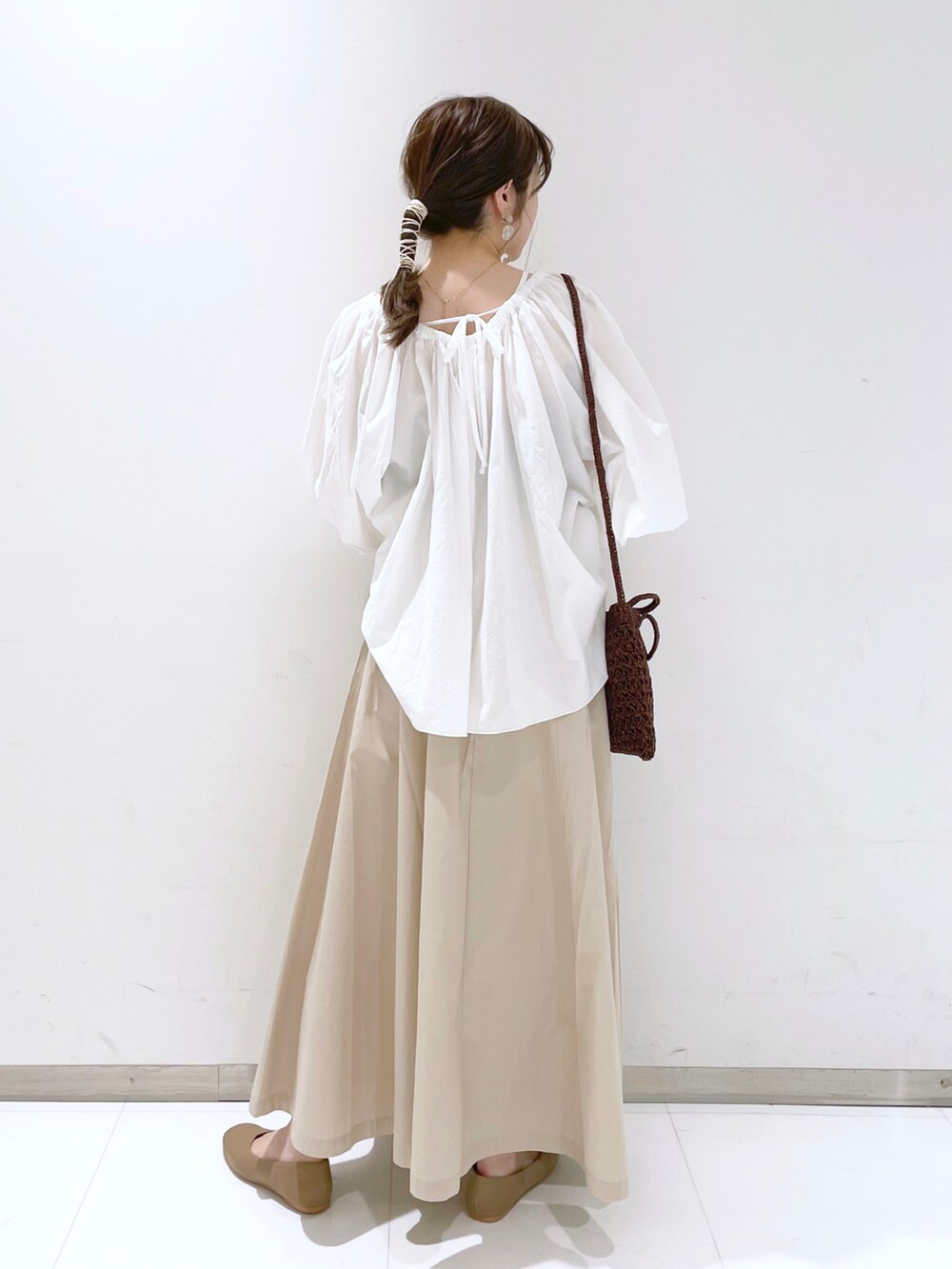 ブラウン系のショルダーバッグ、ベージュ系のパンプス、ホワイト系のスカートを着用したレディースの春コーディネートの2枚目の写真