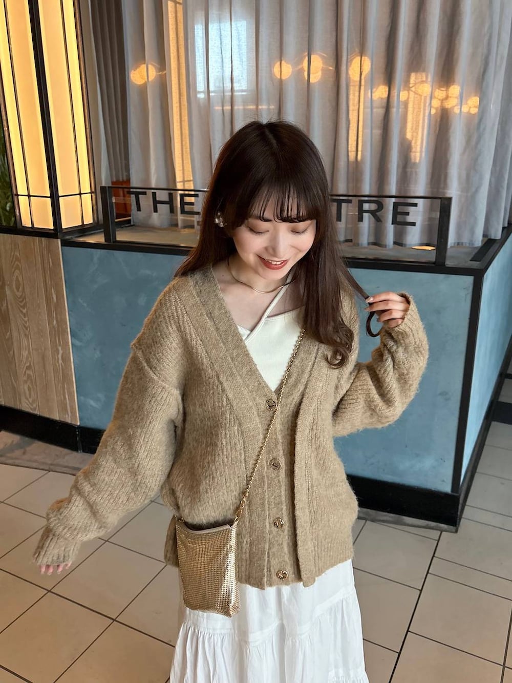 ゴールド系のショルダーバッグ、ブラウン系のローファー、ホワイト系のスカートを着用したレディースの春コーディネートの5枚目の写真