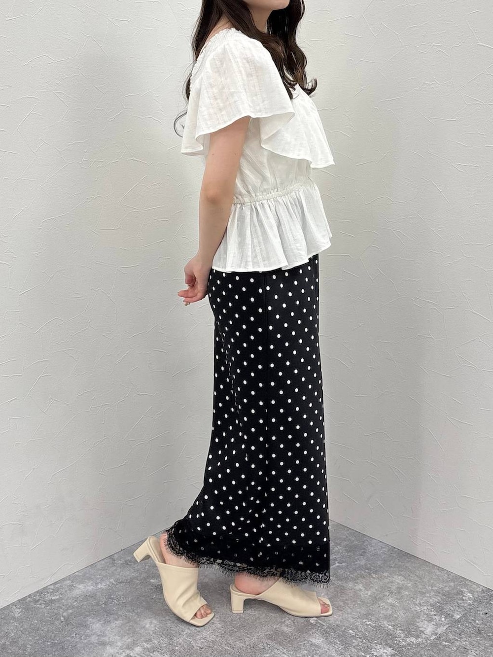 ホワイト系のTシャツ/カットソー、ホワイト系のサンダル、ブラック系のスカートを着用したレディースの春コーディネートの2枚目の写真