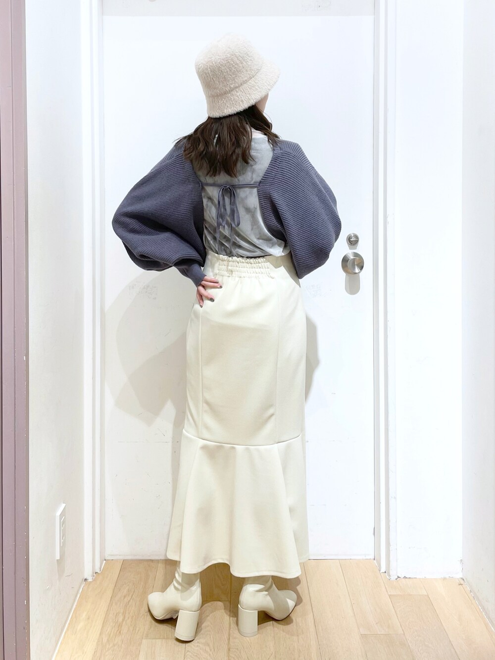 ホワイト系のショルダーバッグ、ホワイト系のブーツ、ブルー系のカーディガン/ボレロを着用したレディースの春コーディネートの2枚目の写真