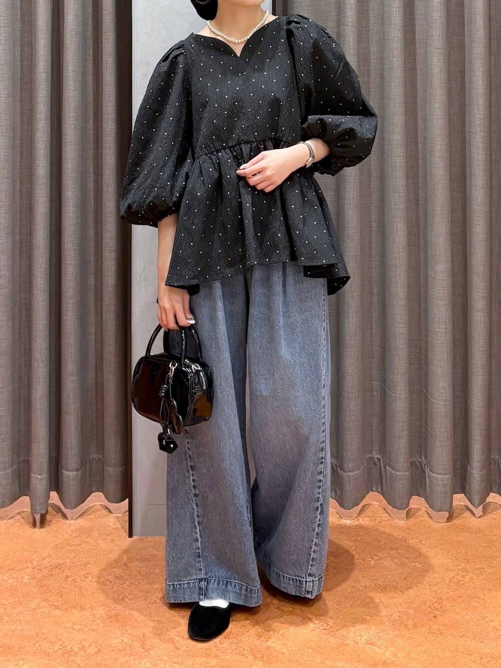 ブラック系のボストンバッグ、ブラック系のシャツ/ブラウス、ブルー系のデニムパンツを着用したレディースの冬コーディネートの3枚目の写真