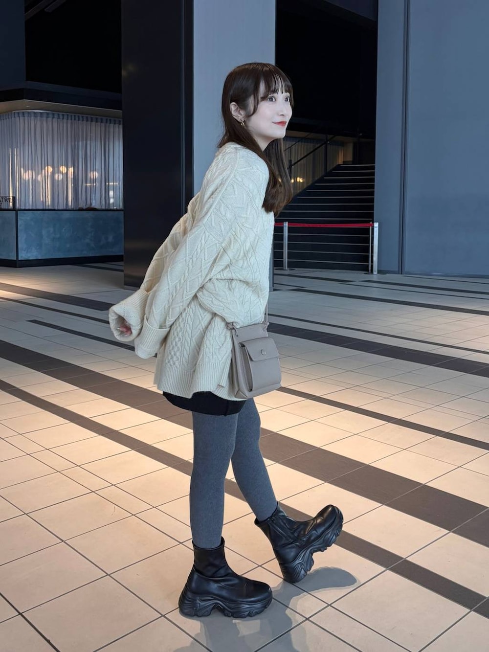 ブラック系のブーツ、ホワイト系のニット/セーター、ベージュ系のイヤリングを着用したレディースの冬コーディネートの2枚目の写真