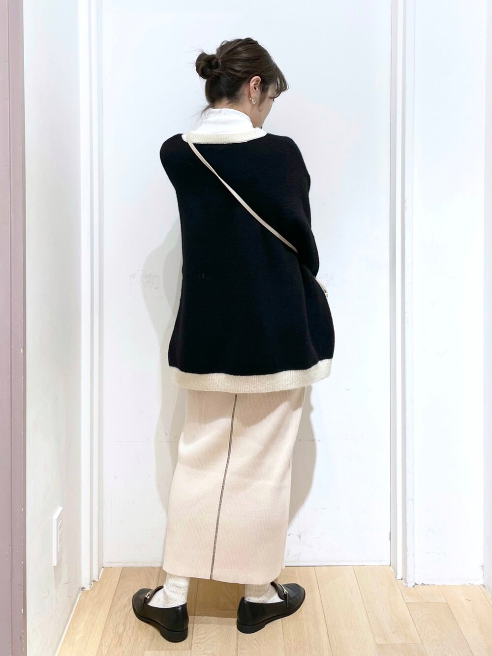 ブラック系のローファー、ホワイト系のスカート、ホワイト系のショルダーバッグを着用したレディースの冬コーディネートの2枚目の写真