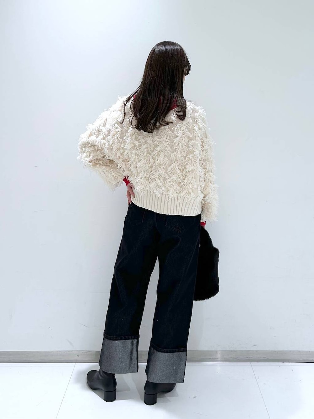 レッド系のニット/セーター、ブラック系のブーツ、ブラック系のショルダーバッグを着用したレディースの冬コーディネートの4枚目の写真