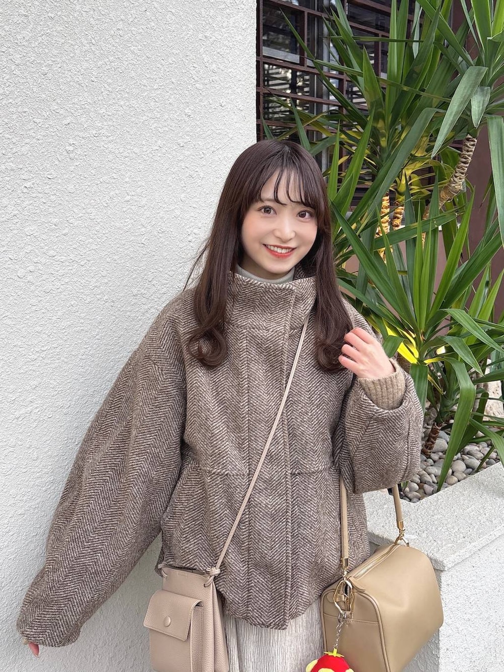 ベージュ系のブルゾン、ゴールド系のボストンバッグ、ホワイト系のスカートを着用したレディースの冬コーディネートの2枚目の写真