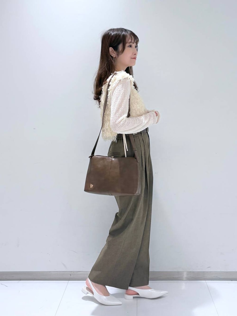 ブラウン系のスラックス、ホワイト系のパンプス、ホワイト系のTシャツ/カットソーを着用したレディースの春コーディネートの3枚目の写真