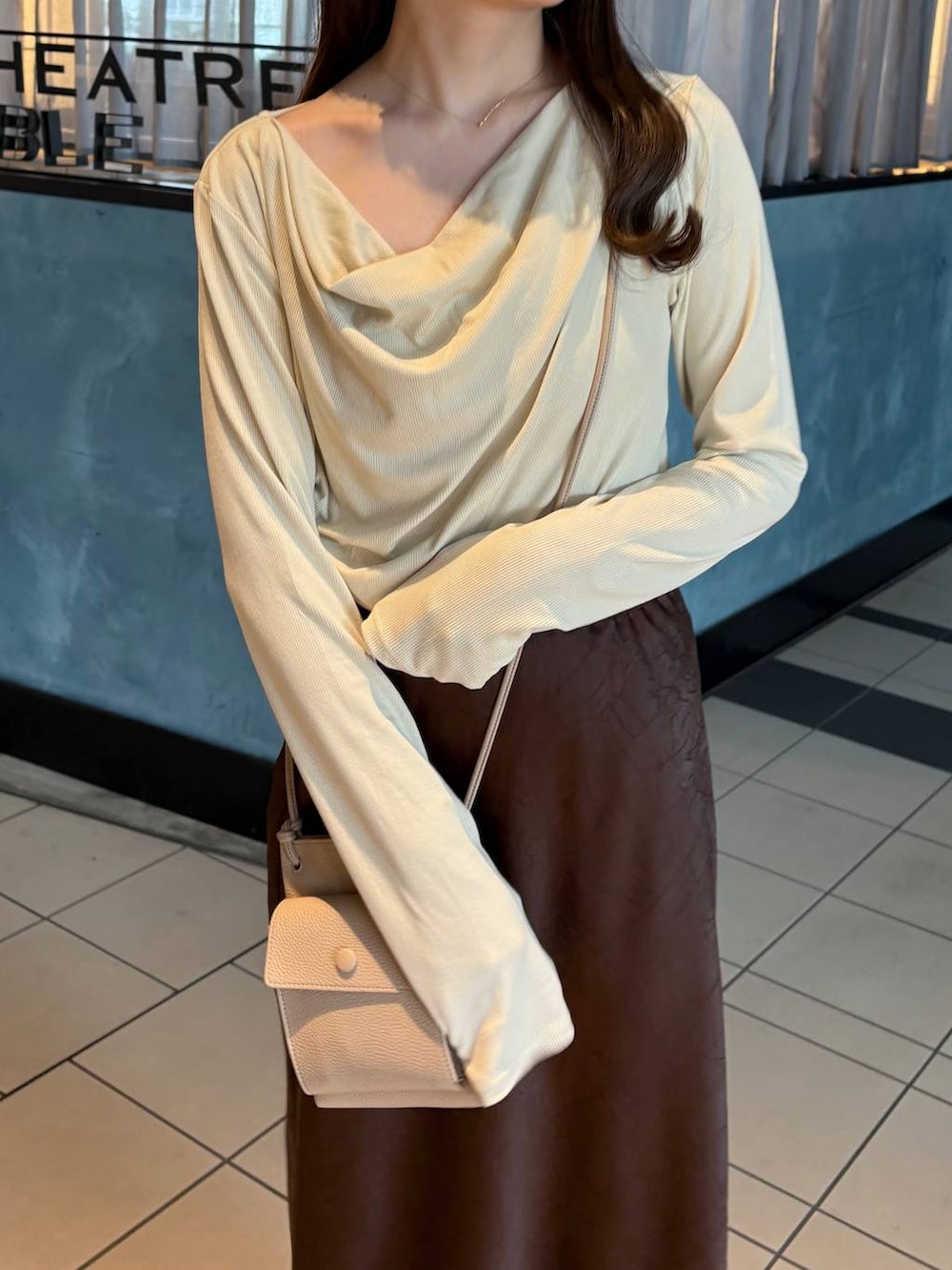 ブラウン系のスカート、ホワイト系のパンプス、ベージュ系のTシャツ/カットソーを着用したレディースの冬コーディネートの2枚目の写真