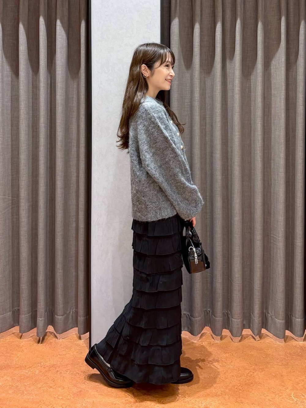 ブラック系のスカート、ブラック系のローファー、ブラック系のボストンバッグを着用したレディースの秋コーディネートの3枚目の写真