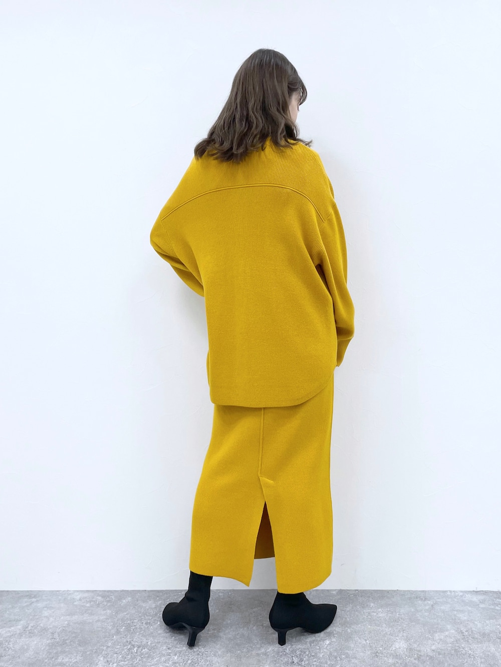 ブラック系のパンプス、イエロー系のワンピース、ホワイト系のTシャツ/カットソーを着用したレディースの冬コーディネートの2枚目の写真