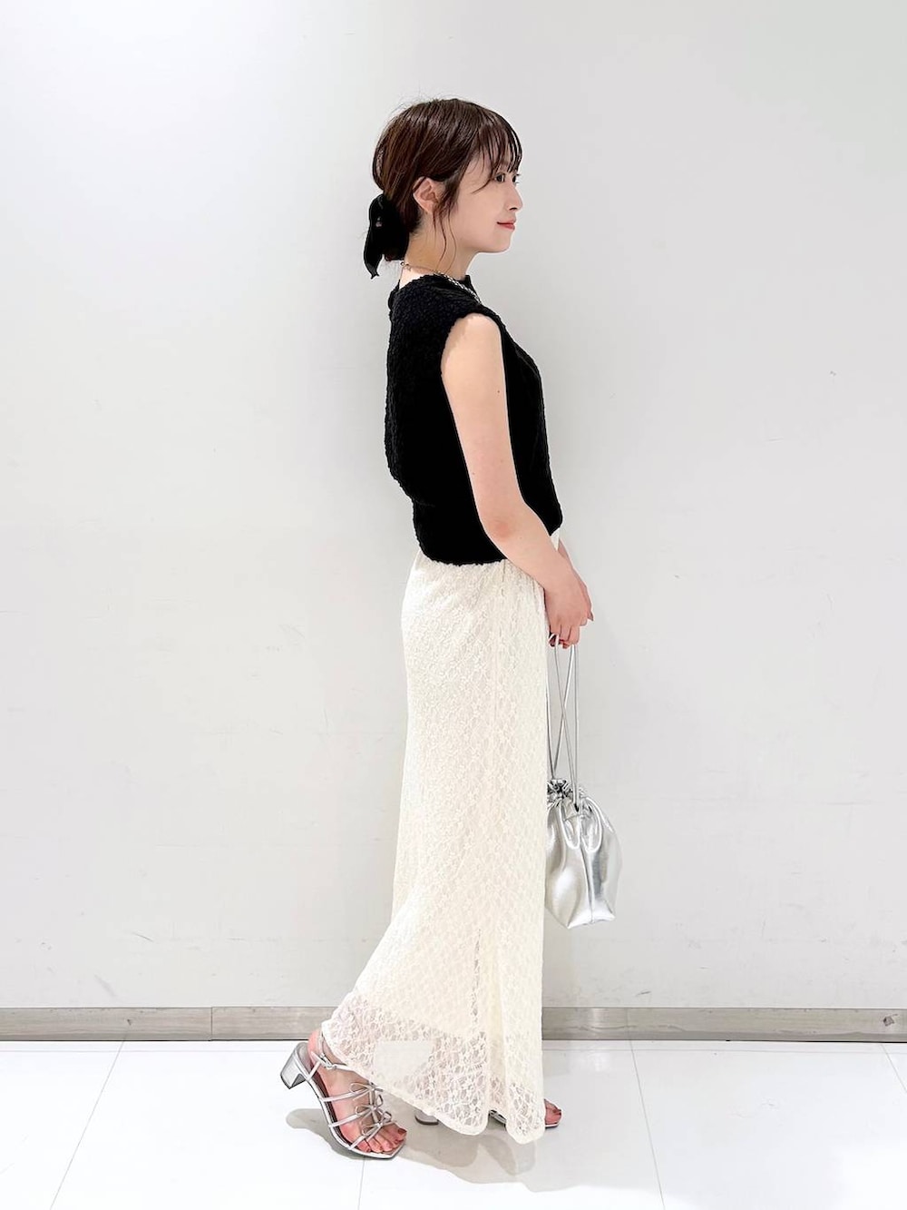 シルバー系のサンダル、ホワイト系のスカート、ブラック系のベストを着用したレディースの夏コーディネートの4枚目の写真