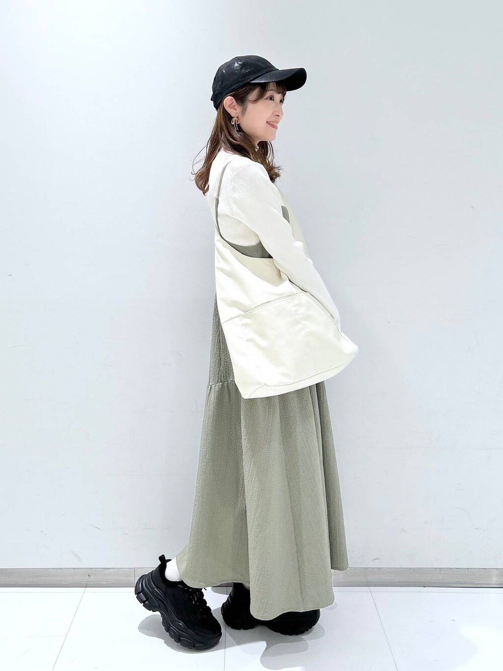 グリーン系のワンピース、ホワイト系のニット/セーター、ブラック系のスニーカーを着用したレディースの冬コーディネートの4枚目の写真