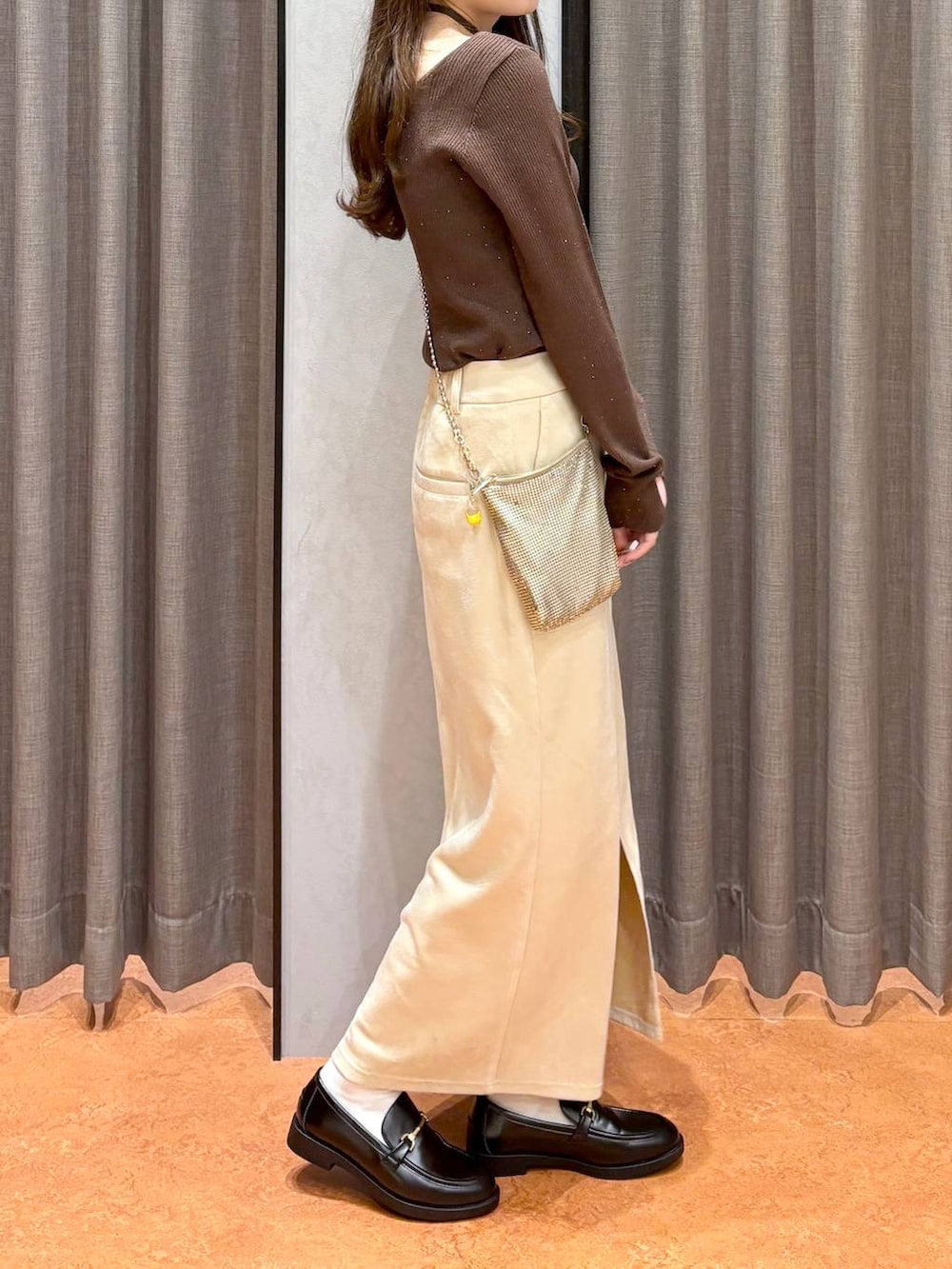 ゴールド系のショルダーバッグ、ホワイト系のスカート、ブラック系のローファーを着用したレディースの秋コーディネートの3枚目の写真