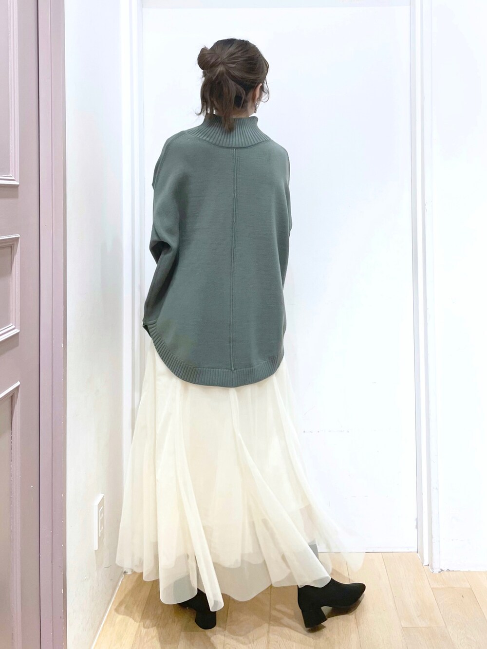 グリーン系のニット/セーター、ホワイト系のスカート、ブラック系のパンプスを着用したレディースの冬コーディネートの2枚目の写真