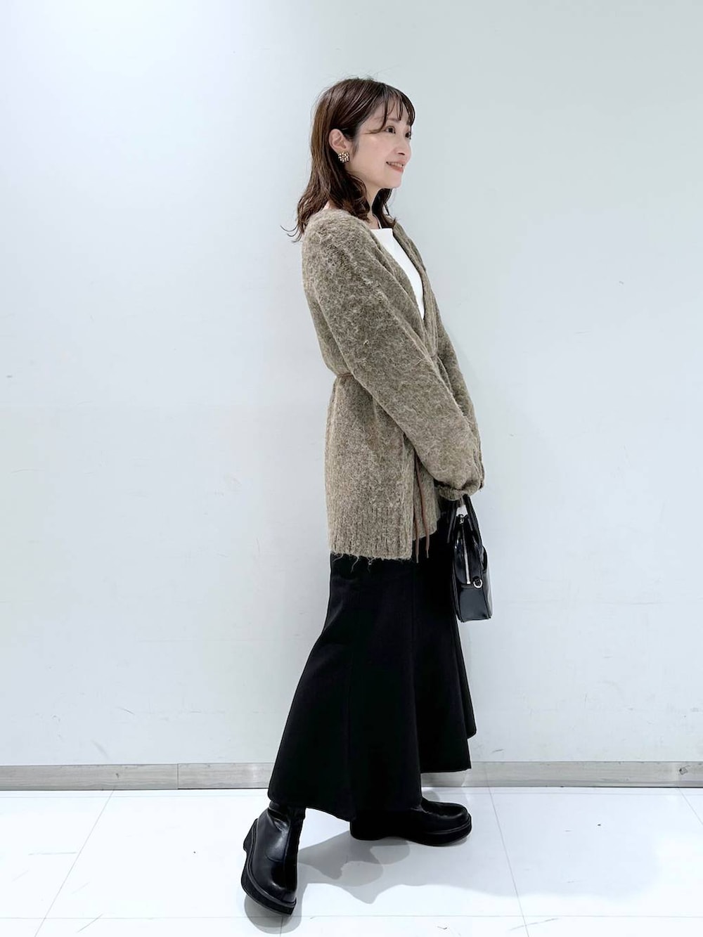 ホワイト系のTシャツ/カットソー、ブラック系のブーツ、ブラック系のスカートを着用したレディースの秋コーディネートの3枚目の写真