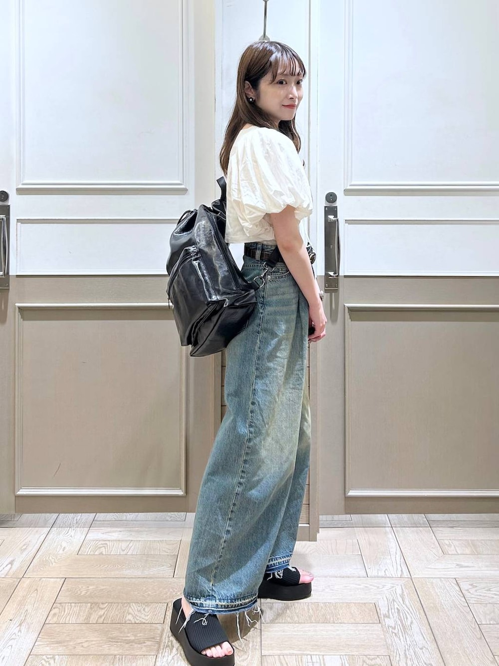 ホワイト系のTシャツ/カットソー、ブラック系のサンダル、ブルー系のデニムパンツを着用したレディースの春コーディネートの6枚目の写真